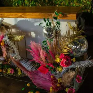 Decorative setup with Acrylic Bar, disco balls, colorful flowers, and foliage for an event.