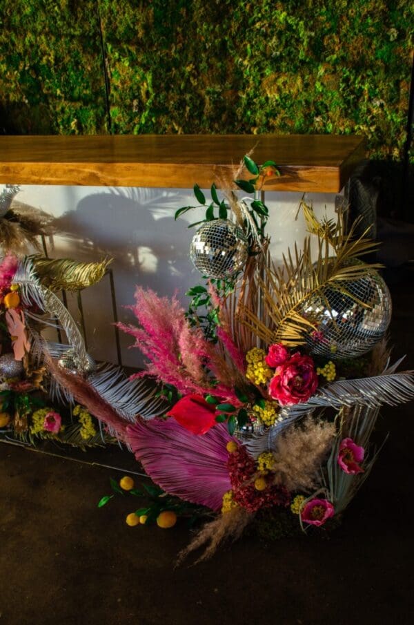 Decorative setup with Acrylic Bar, disco balls, colorful flowers, and foliage for an event.