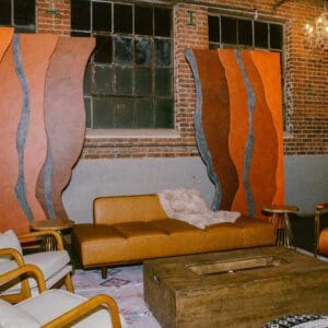 Vintage-style living room with a brown sofa, armchairs, and abstract wall art in an industrial space with Red Rocks Entrance Walls.