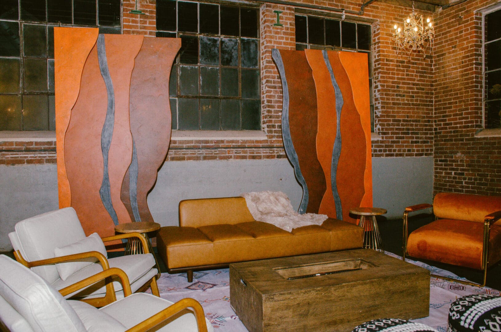 Vintage-style living room with a brown sofa, armchairs, and abstract wall art in an industrial space with Red Rocks Entrance Walls.