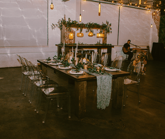 Elegantly set dining table for a formal event with ambient lighting and a musician in the background.