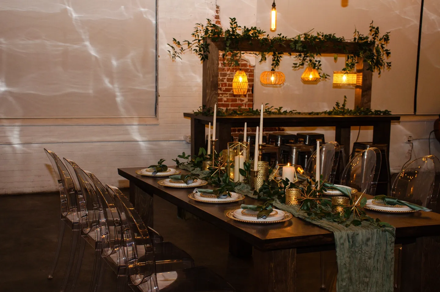 Elegant event dining setup with clear chairs, greenery, and warm lighting.